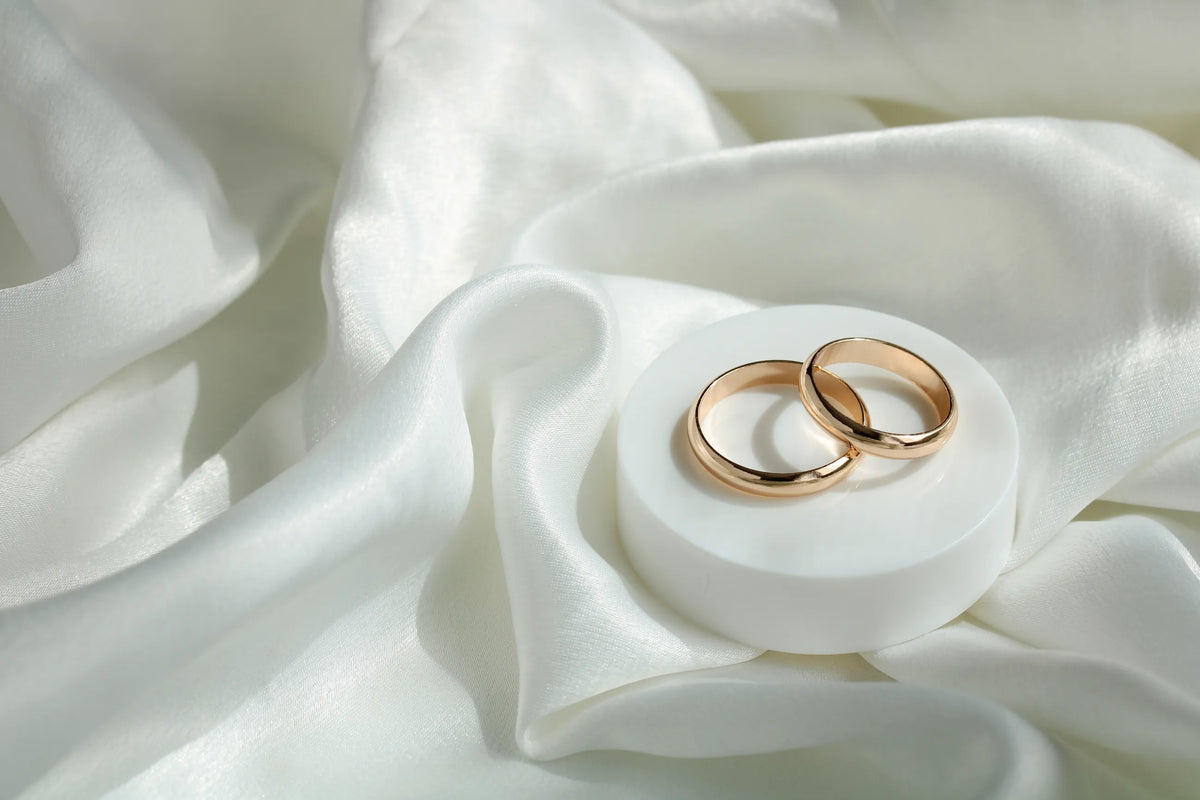 Two gold wedding bands on white silk