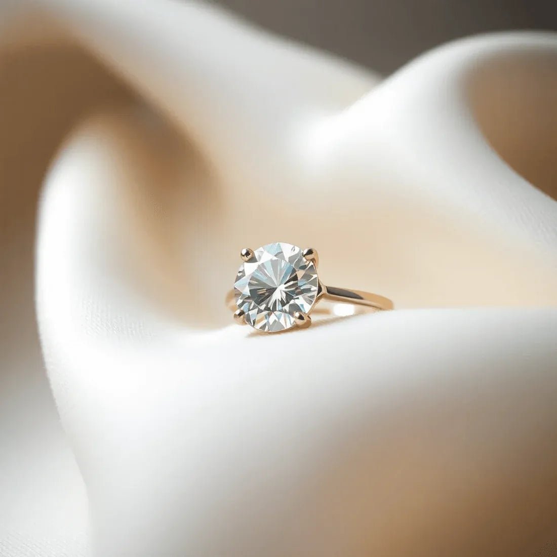 Round diamond solitaire engagement ring on cream silk
