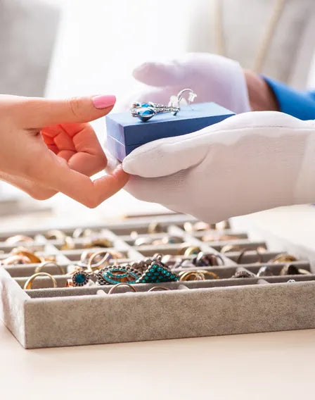 Specialist presenting a ring box over a tray of jewelry