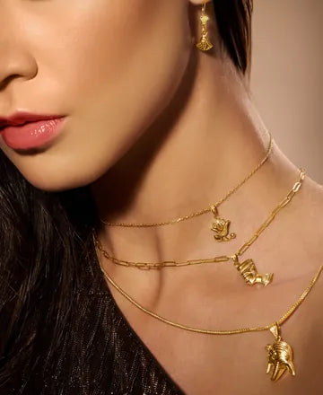 Model wearing gold pendant necklaces