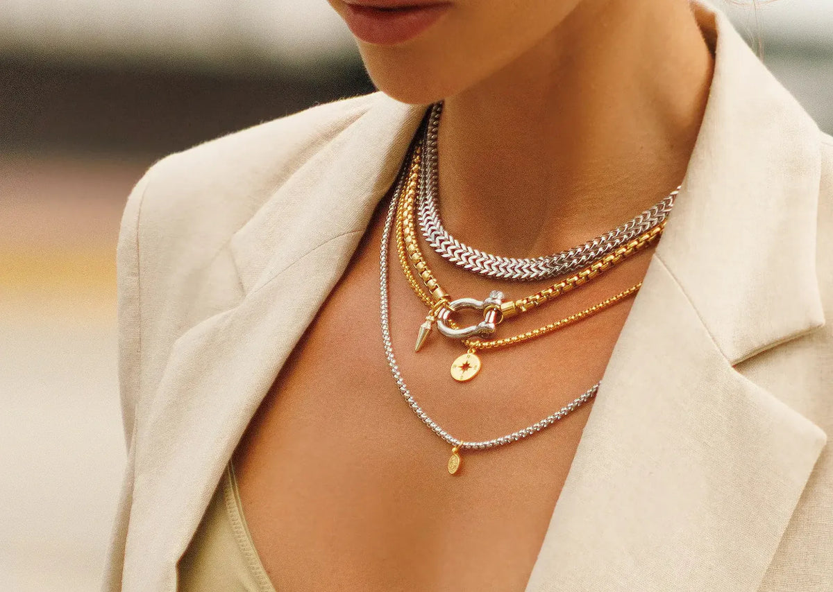 Model wearing layered gold and silver chain necklaces